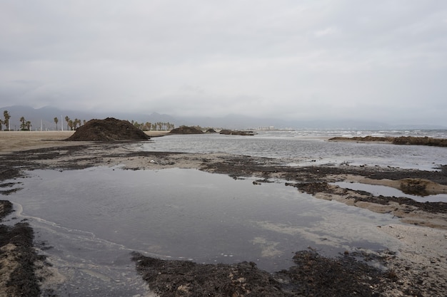 Plano amplio de una orilla del mar con un montón de arena negra