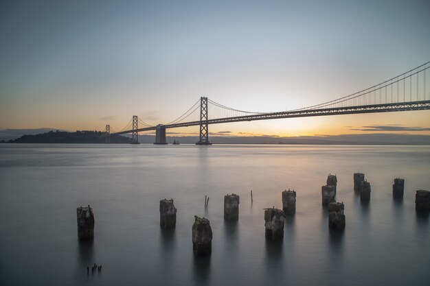 Plano amplio del puente de la bahía en el cuerpo de agua durante el amanecer en San Francisco, California