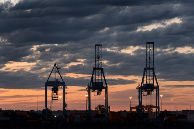 Plano amplio de tres torres en un puerto durante la puesta de sol en un día nublado