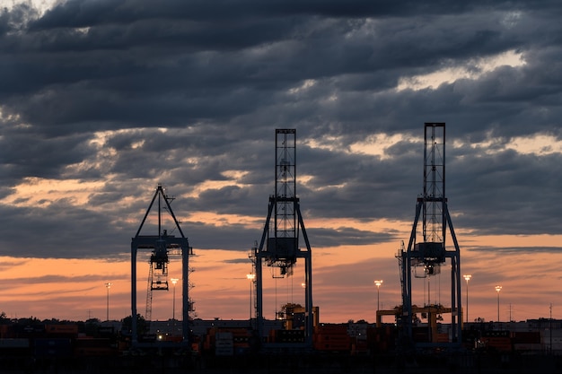 Plano amplio de tres torres en un puerto durante la puesta de sol en un día nublado
