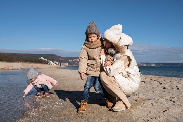 Plano completo madre e hijos en la playa