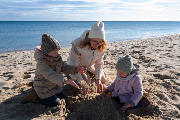 Plano completo madre e hijos en la playa