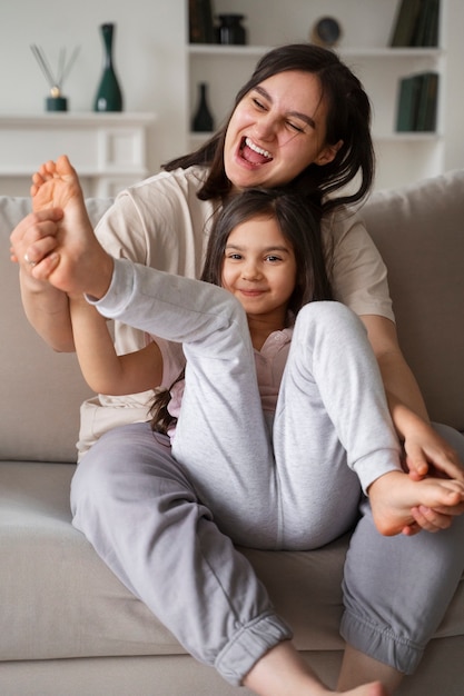 Plano completo madre haciendo cosquillas en los pies del niño