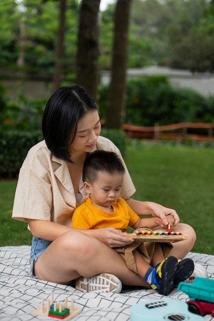 Foto gratuita plano completo madre y niño sentados en tela