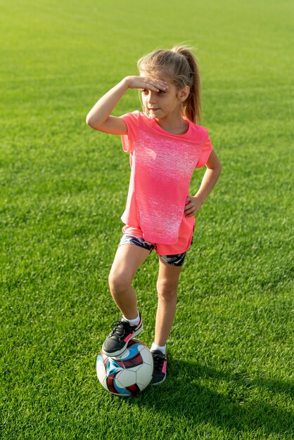 Plano completo de niña con camiseta rosa y bola