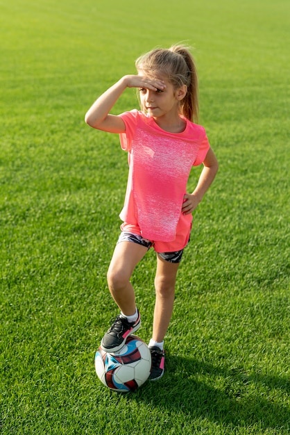 Plano completo de niña con camiseta rosa y bola