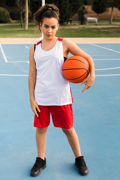 Plano completo de niña con pelota de baloncesto