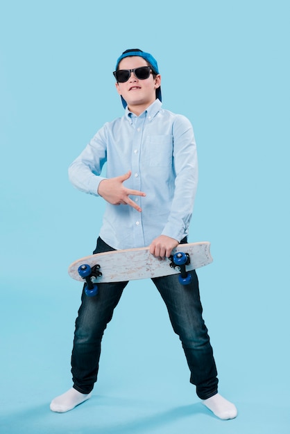 Plano completo del niño moderno con gafas de sol y patineta