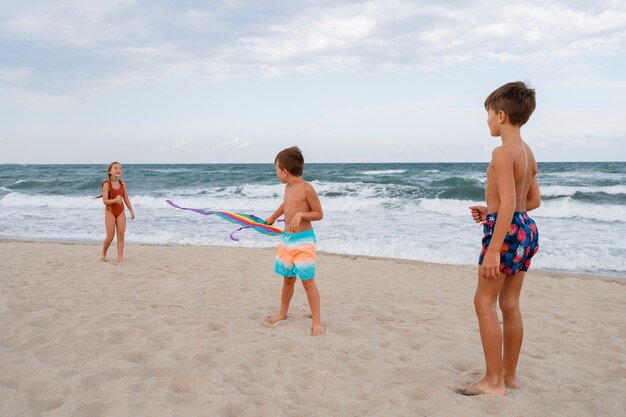 Plano completo de niños pequeños divirtiéndose en la playa.