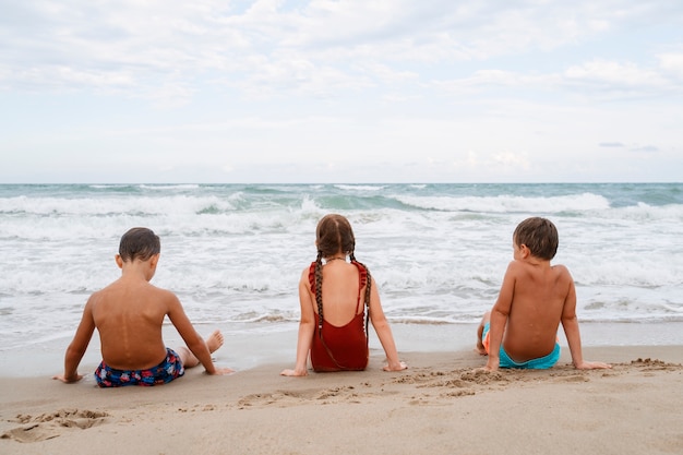 Plano completo de niños pequeños divirtiéndose en la playa.