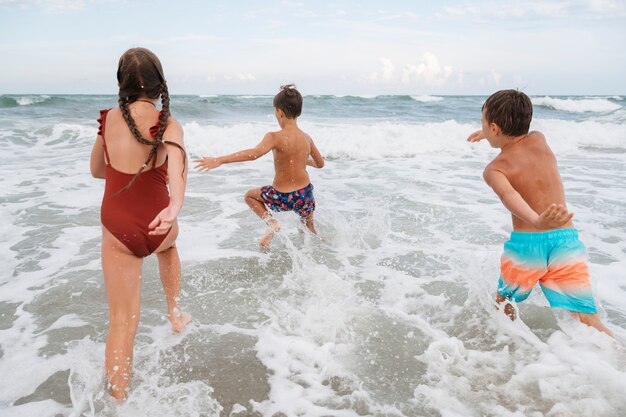 Plano completo de niños pequeños divirtiéndose en la playa.