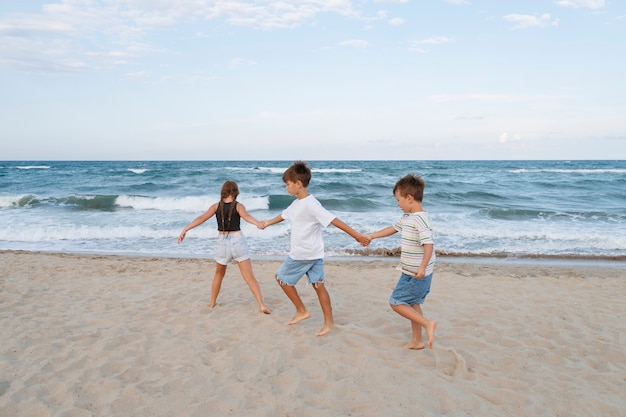Plano completo de niños pequeños divirtiéndose en la playa.
