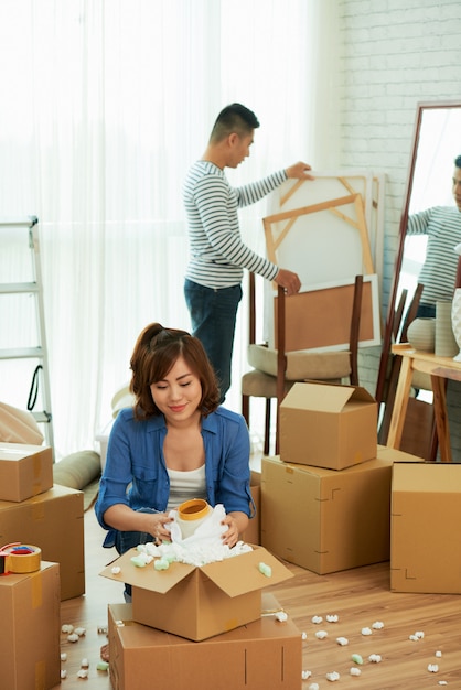 Plano completo de una pareja desempacando pertenencias en un apartamento nuevo