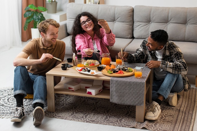 Plano completo de personas comiendo sushi en casa.