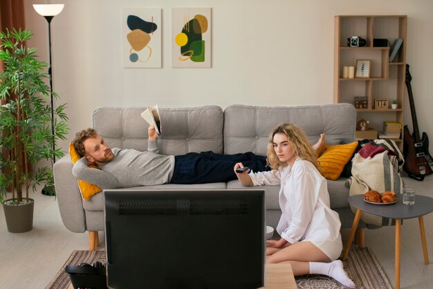 Plano completo de personas viendo la televisión en la sala de estar