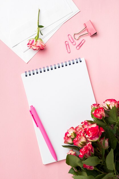 Plano de escritorio con cuaderno y ramo de rosas