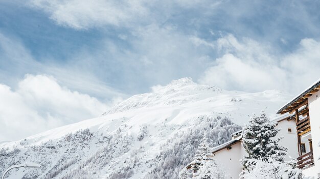 Plano general de una casa blanca y marrón cerca de árboles y una montaña cubierta de nieve