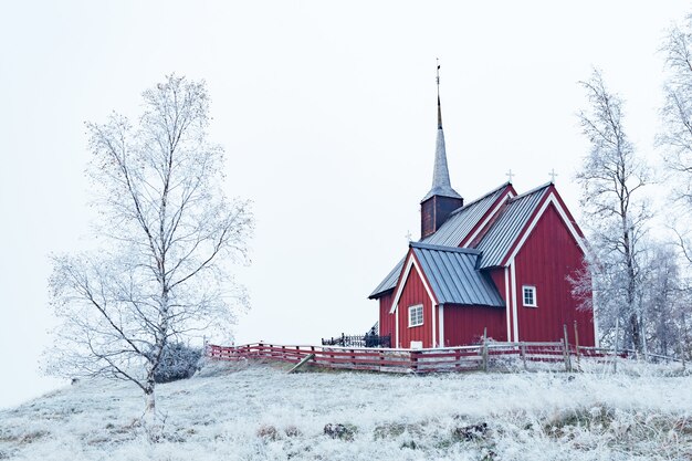 Plano general de un edificio rojo en una zona nevada rodeada de árboles desnudos cubiertos de nieve bajo un cielo despejado