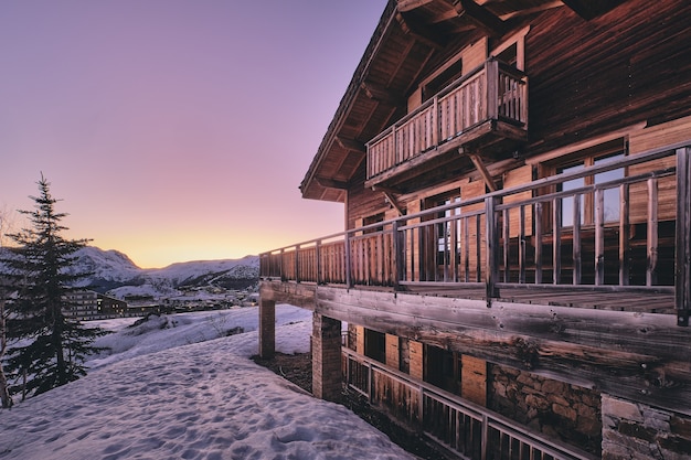 Plano general de la fachada de una cabaña en la estación de esquí Alpe d Huez en los Alpes franceses durante el amanecer