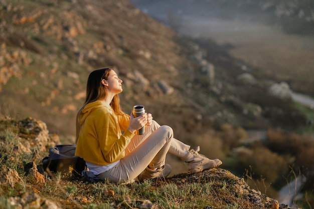 Plano general de mujer joven disfrutando de la naturaleza que la rodea