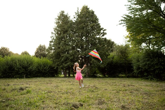 Plano general de niña feliz divirtiéndose con una cometa