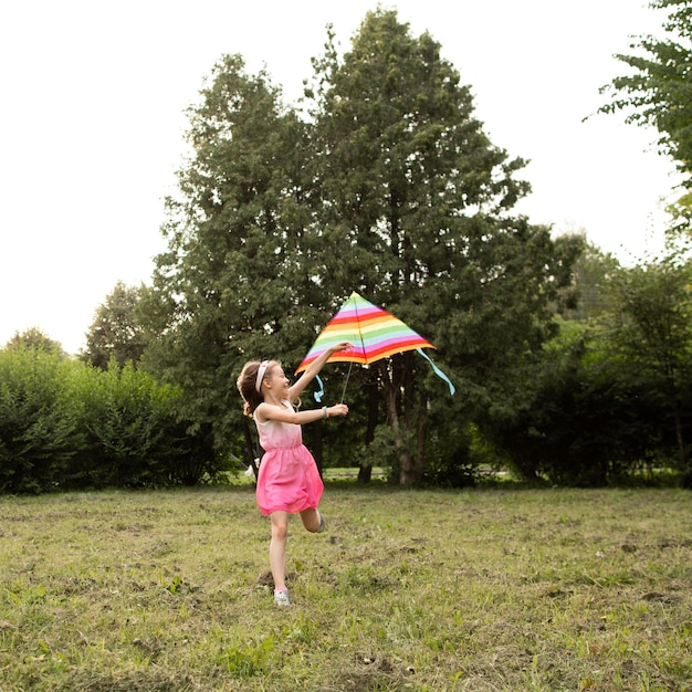 Plano general de niña feliz divirtiéndose con una cometa