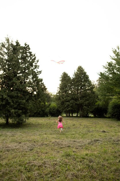 Plano general de niña feliz divirtiéndose con una cometa