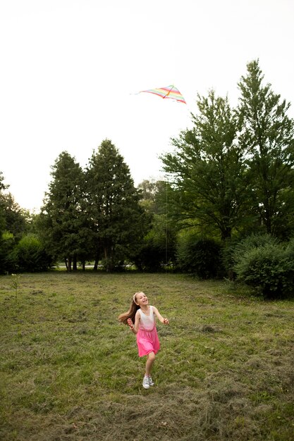 Plano general de niña feliz divirtiéndose con una cometa