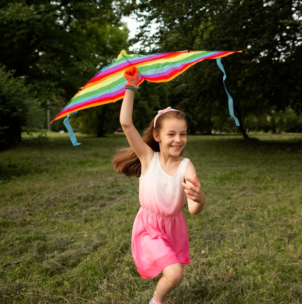 Plano general de niña feliz divirtiéndose con una cometa