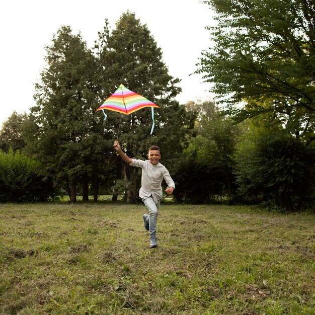 Plano general de niño feliz divirtiéndose con una cometa