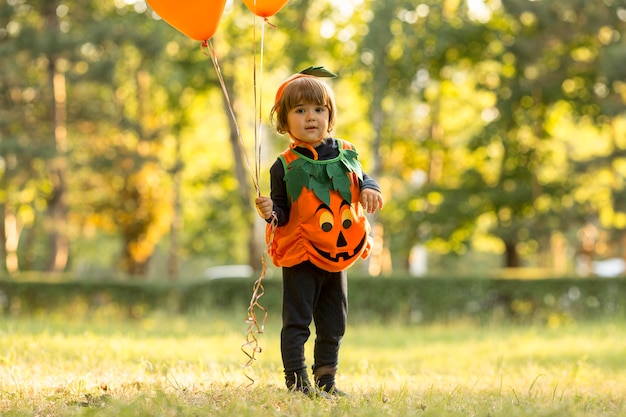 Plano general de niño lindo en traje de calabaza