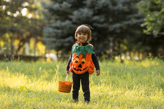 Plano general de niño lindo en traje de calabaza