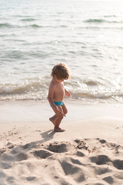 Plano general de un niño mirando hacia la playa.