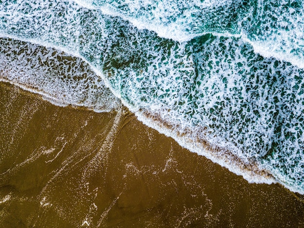 Plano general de las olas del mar azul en una playa de arena