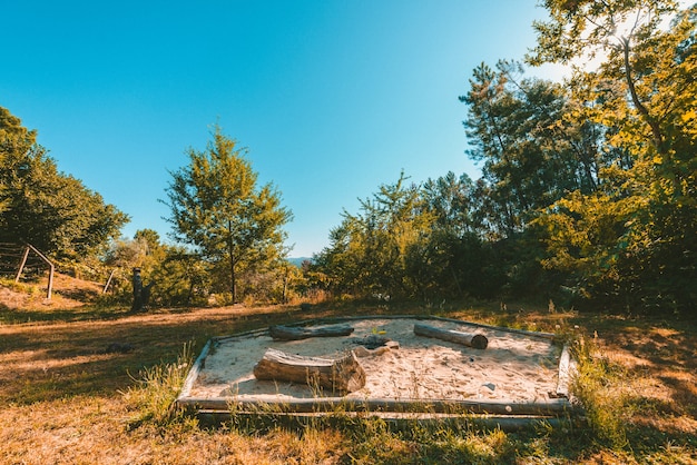 Foto gratuita plano general de un parque con una hoguera en un arenero rodeado de plantas y árboles