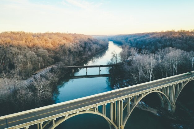 Plano general de un pintoresco río bordeado de árboles otoñales y un puente arqueado en primer plano