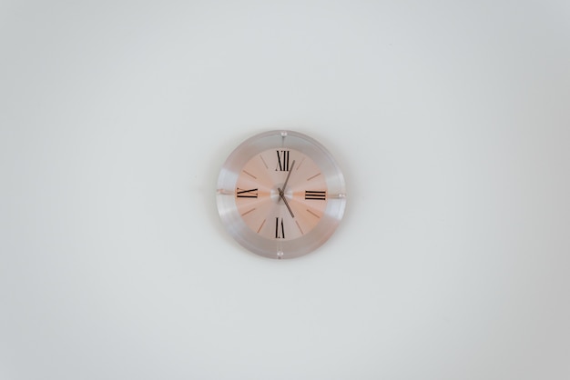 Foto gratuita plano general de un reloj de pared de oro rosa en una pared blanca