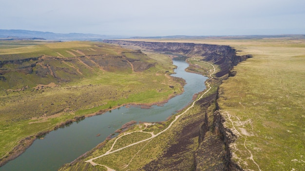 Plano general de un río que fluye entre verdes colinas bajo un cielo despejado