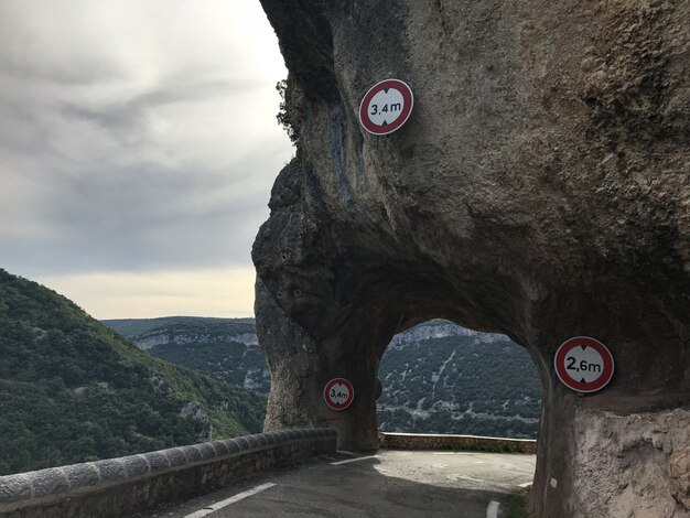 Plano general de una ruta bajo un arco de roca rodeado de montañas cubiertas de árboles