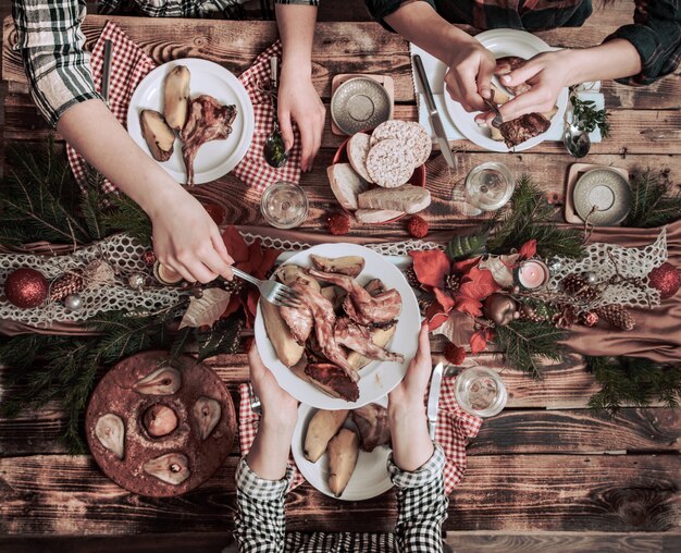 Plano de manos de amigos comiendo y bebiendo juntos. Vista superior de personas que tienen fiesta, reunión, celebrando juntos en la mesa rústica de madera