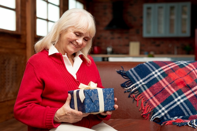 Plano medio, abuela feliz, sosteniendo un regalo