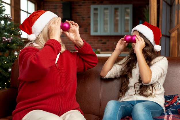 Plano medio abuela y niño jugando con bolas de navidad