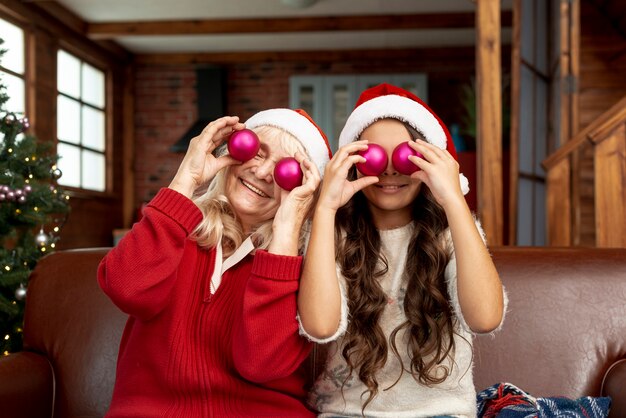 Plano medio abuela y niño posando con bolas de navidad