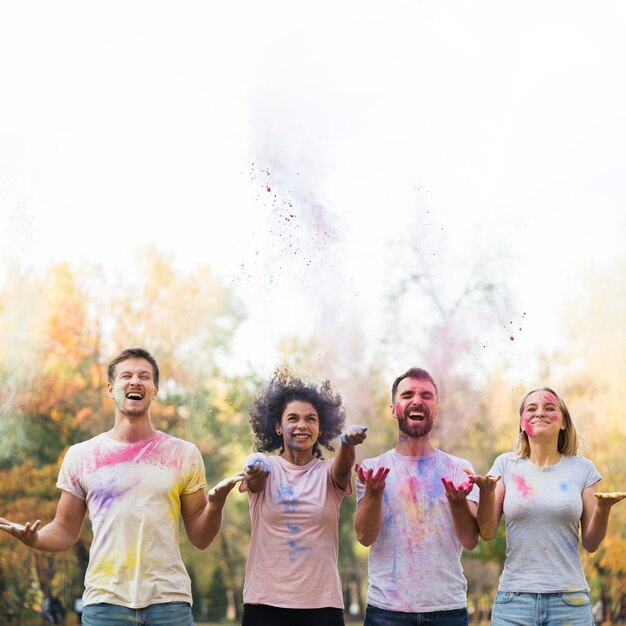 Plano medio de amigos arrojando pintura para holi