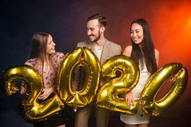 Plano medio de amigos sosteniendo globos en la fiesta de año nuevo