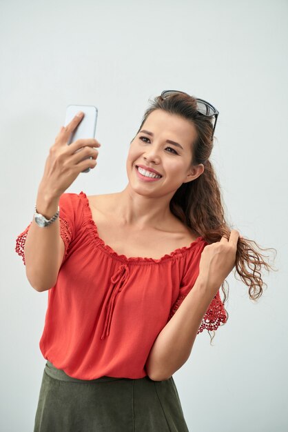 Plano medio de la atractiva dama tomando una selfie con un teléfono inteligente