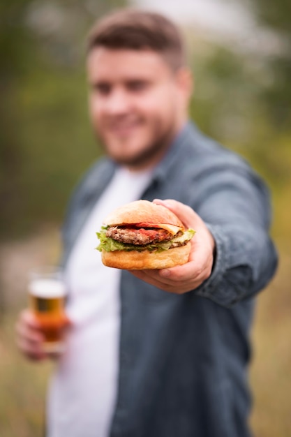 Plano medio borroso hombre sujetando hamburguesa