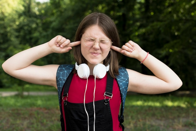 Plano medio de una chica de secundaria cubriendo sus orejas