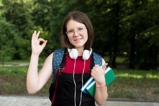 Plano medio de una chica de secundaria feliz sosteniendo libros en las manos