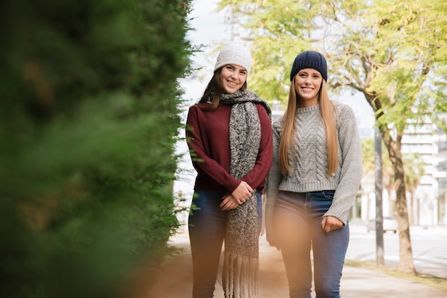 Plano medio de dos mujeres sonrientes caminando en el parque